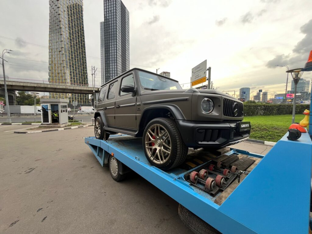 Эвакуатор с лебедкой аккуратно транспортирует новый Mercedes G-Класс по московской трассе.